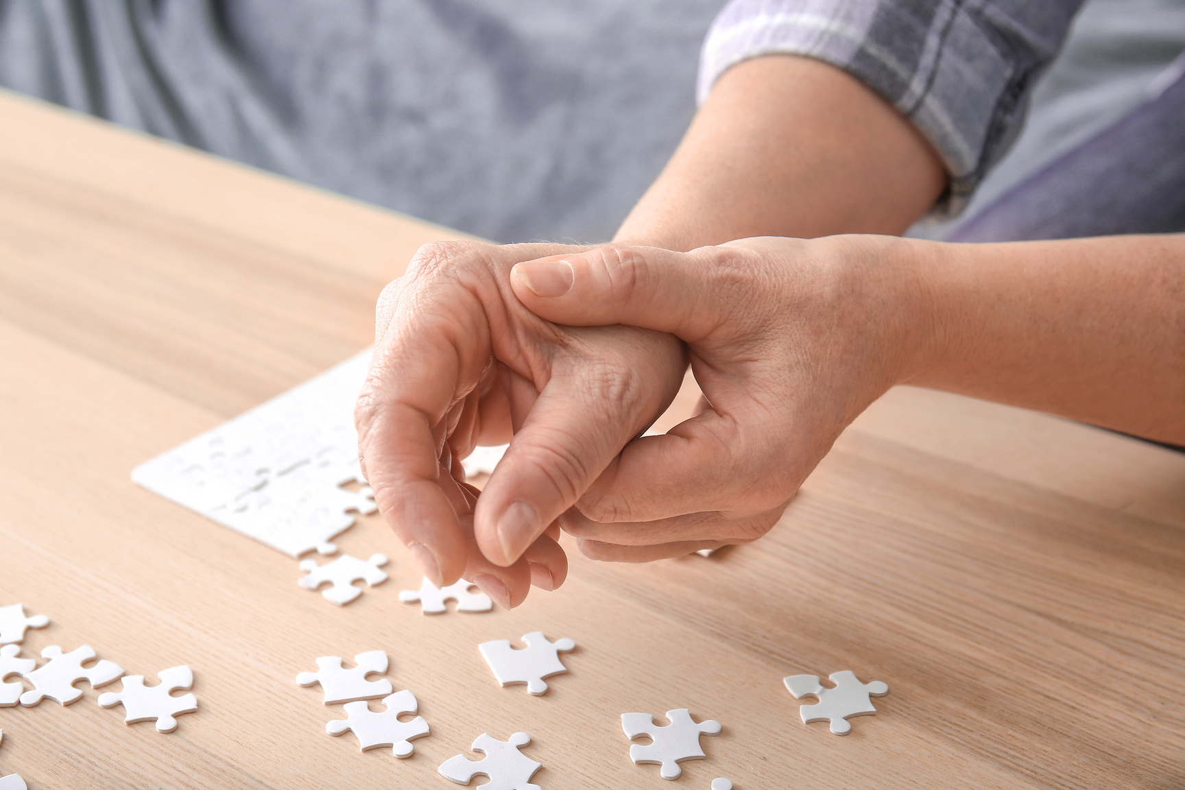 Senior Woman Suffering from Parkinson Syndrome Doing Puzzle at Home